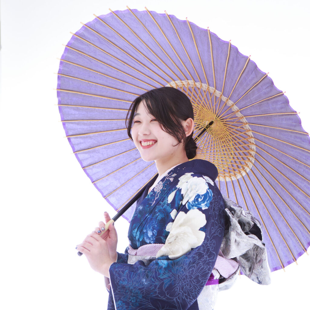 紺色の成人式振袖姿で傘をさしている